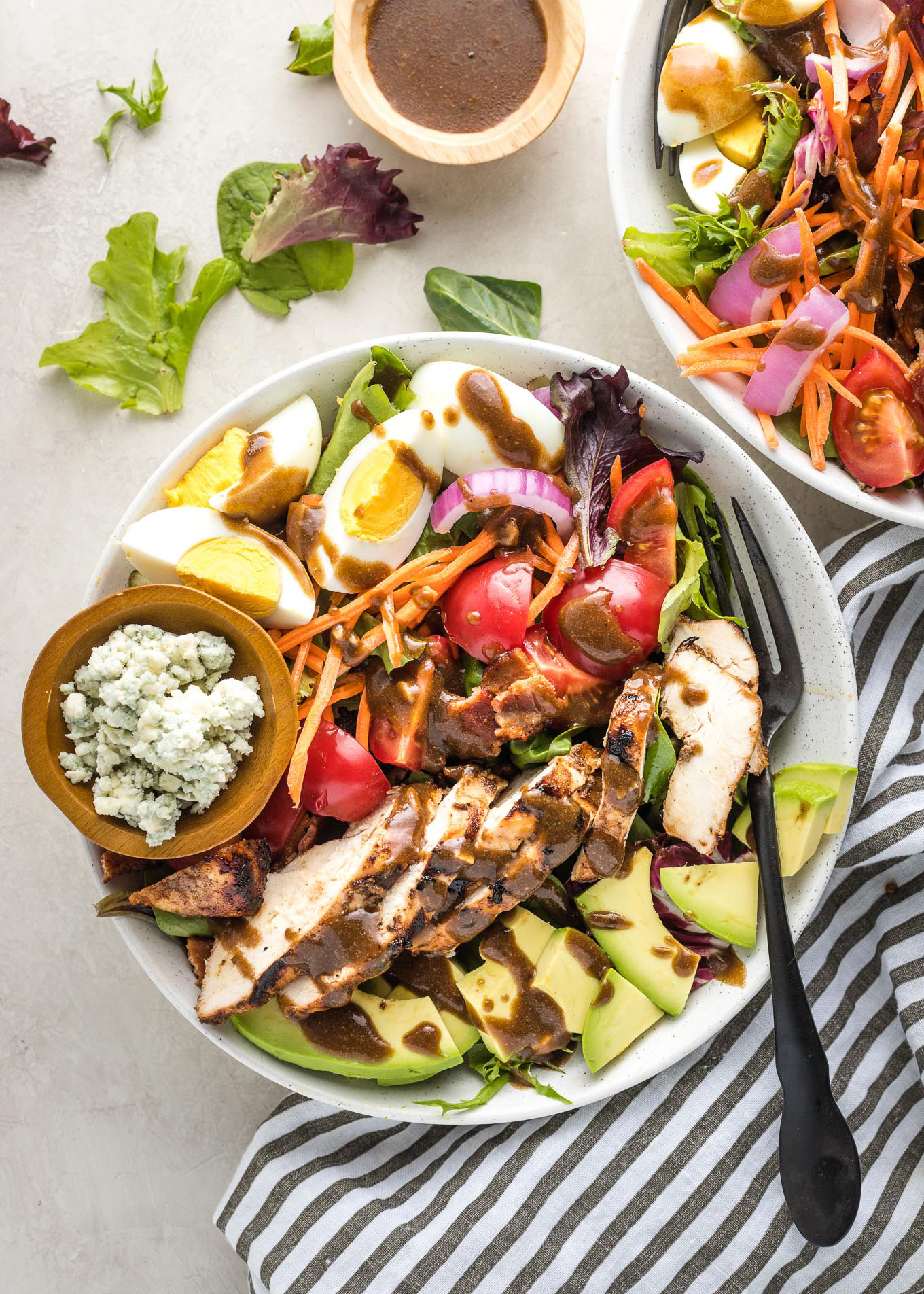 Cobb salads in white bowls served with grilled chicken and balsamic vinaigrette.