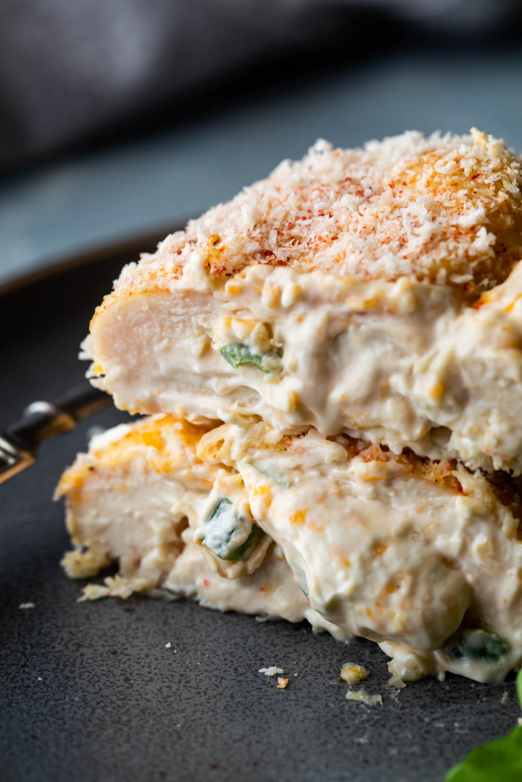 Closeup of Jalapeno popper stuffed chicken sliced in half with filling and cheese oozing out