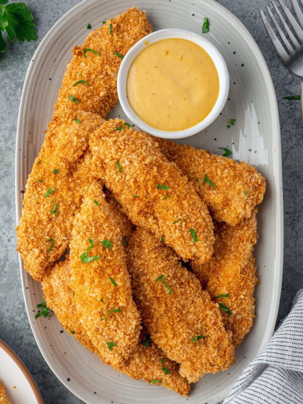 Crispy chicken tenders on a plate with honey mustard.