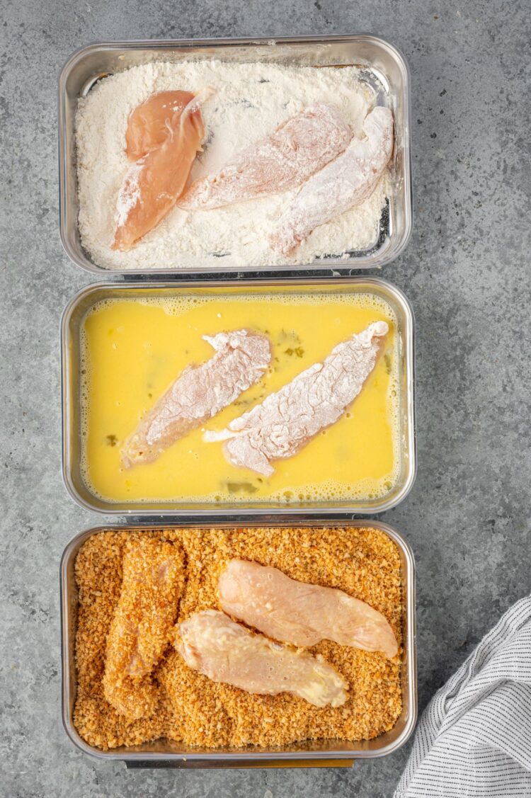 Dredging chicken tenders in flour, eggs and breadcrumbs.