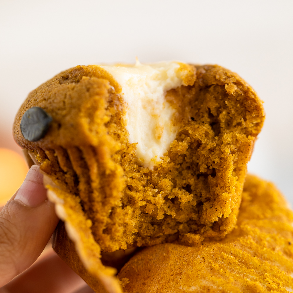 Hand holding a muffin with a cream cheese filling.