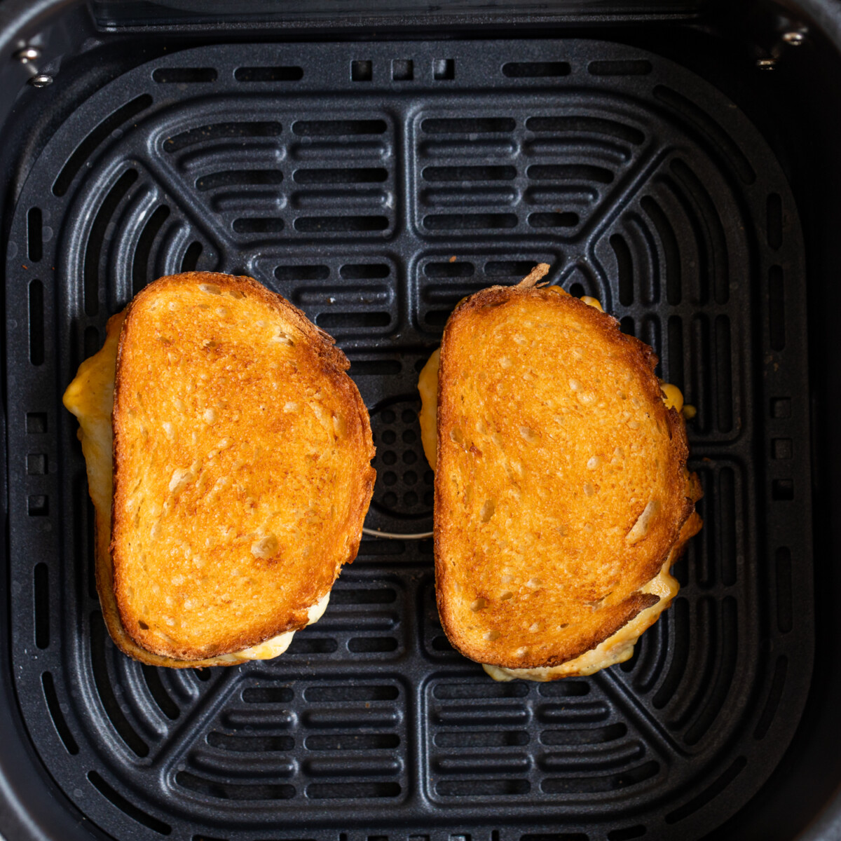 Cooking two grilled cheese sandwiches in an air fryer.