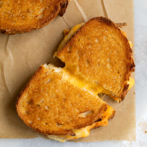 Cheesy grilled cheese sandwich on parchment paper.