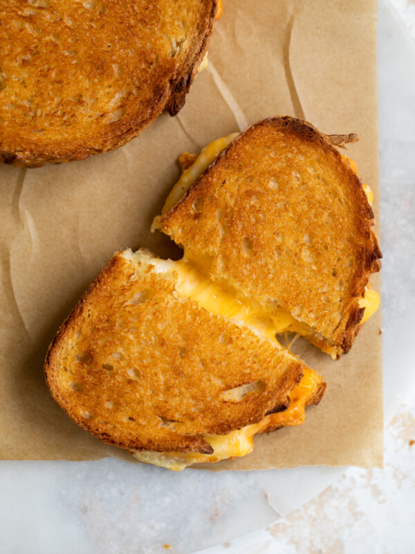 Cheesy grilled cheese sandwich on parchment paper.