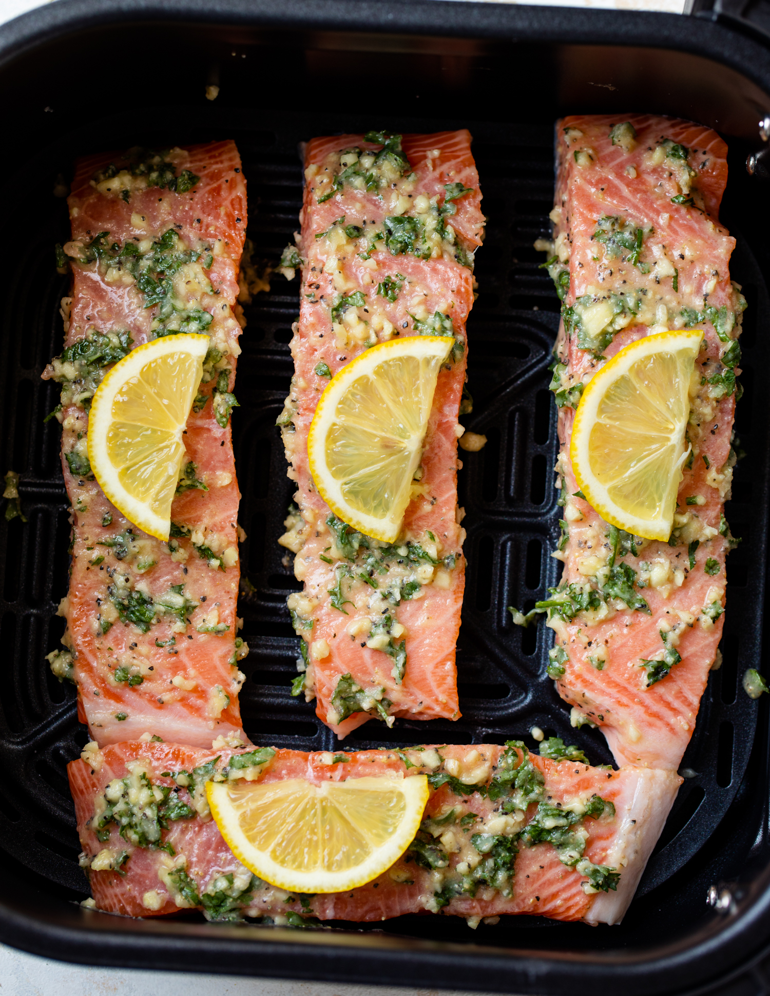 Salmon covered with lemon wedges in an air fryer.