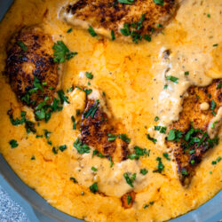Creamy cajun chicken garnished with fresh parsley in a large pan.