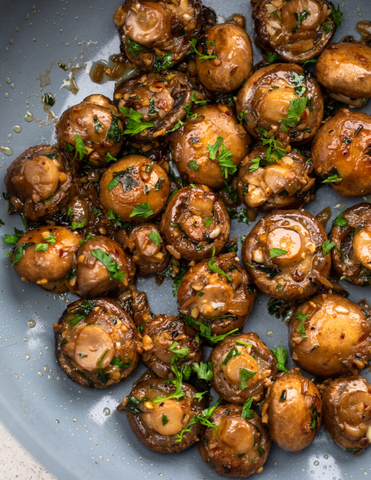 Garlic mushrooms garnished with parsley in a large skillet.