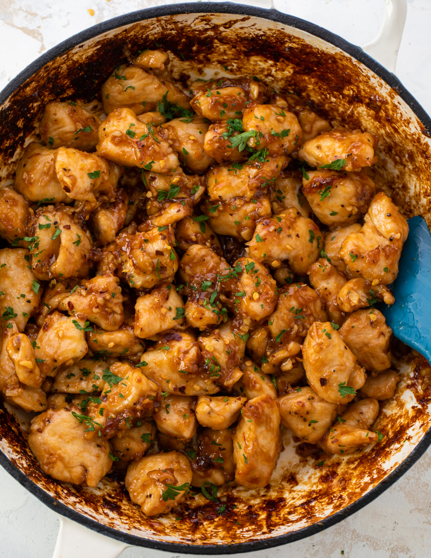 Cooking chicken bites in a sauce in a large pan.