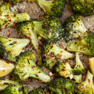 Roasted broccoli on a pan with lemon wedges.