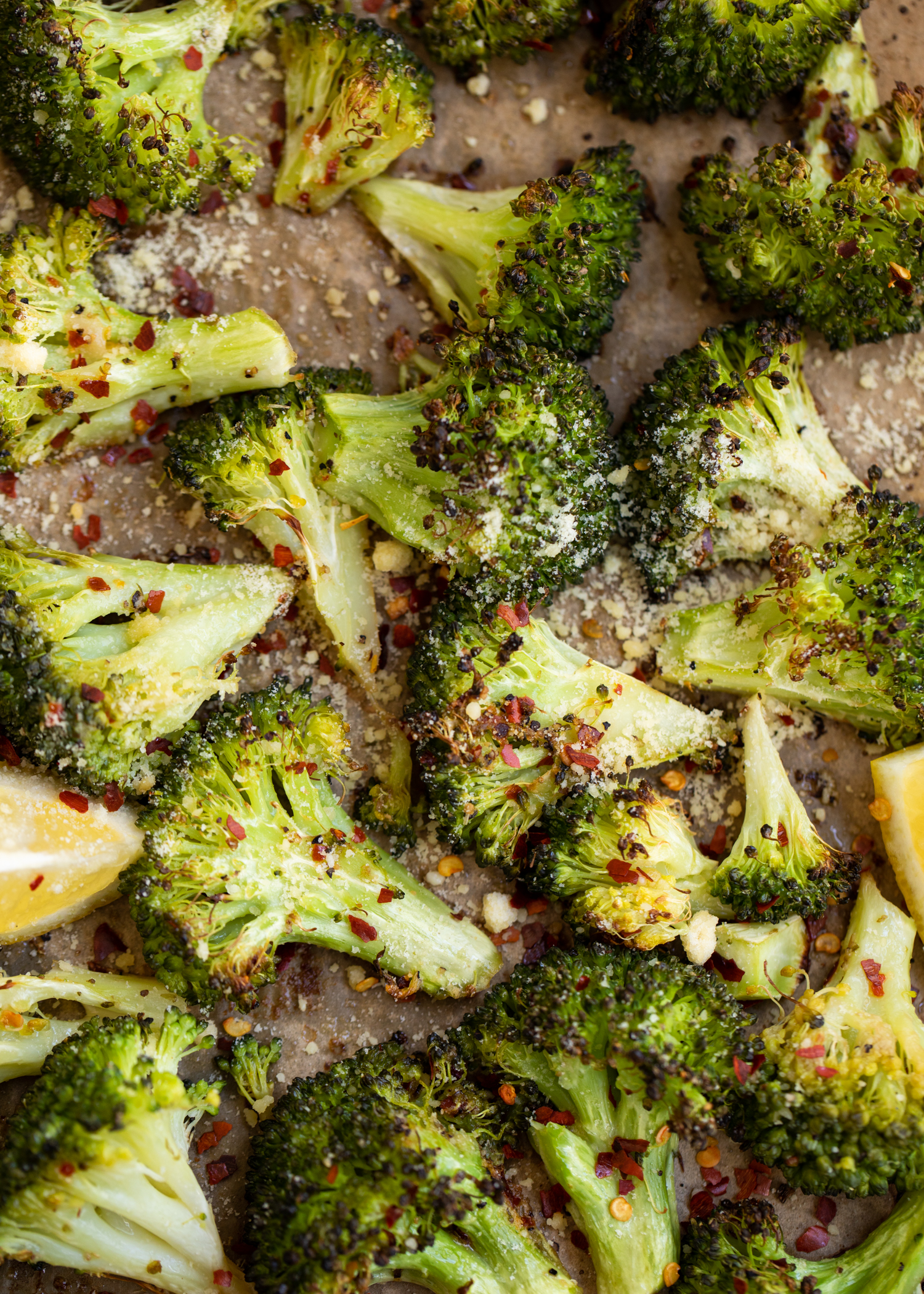 Roasted broccoli on a pan with lemon wedges.