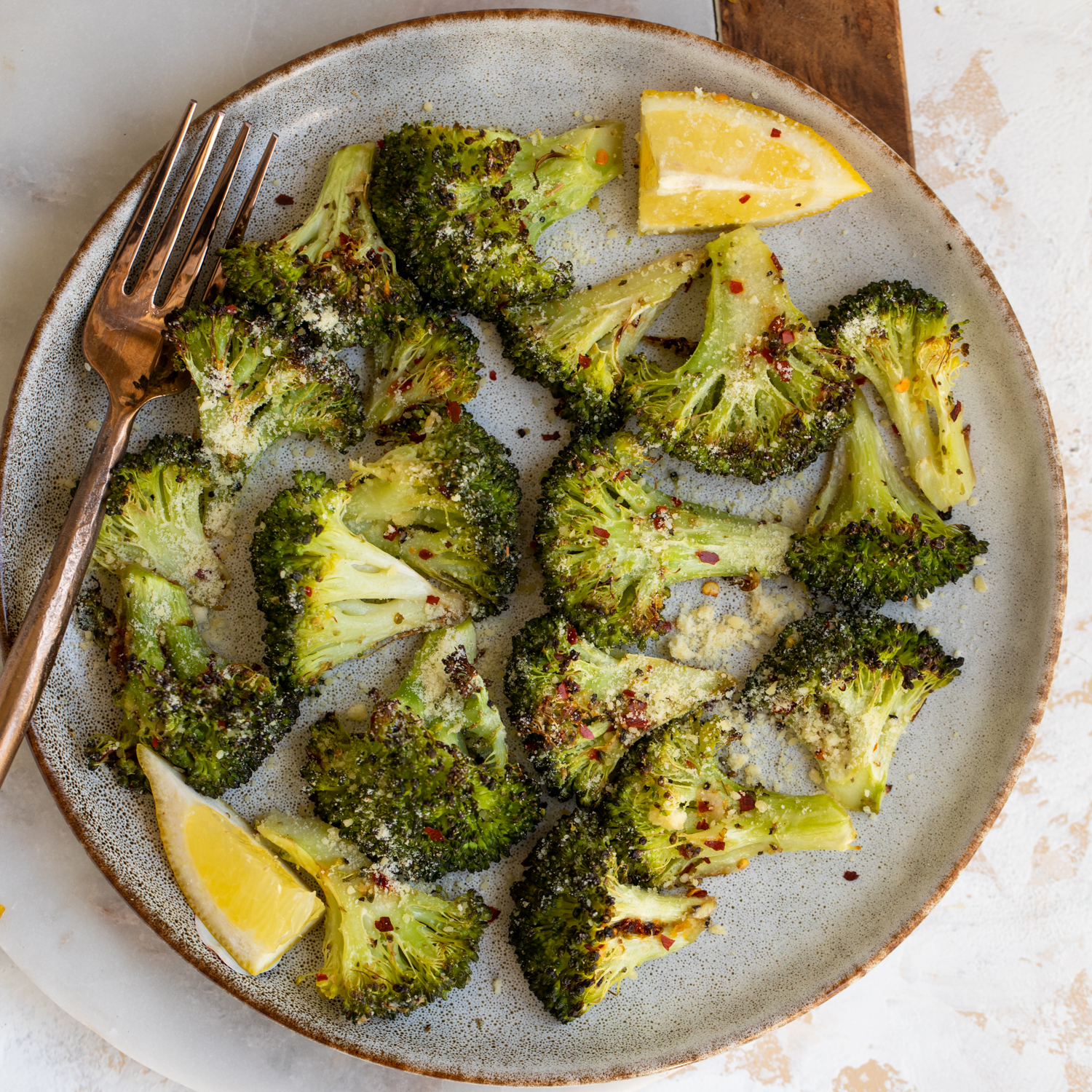 Cooked broccoli florets on a plate with lemon.