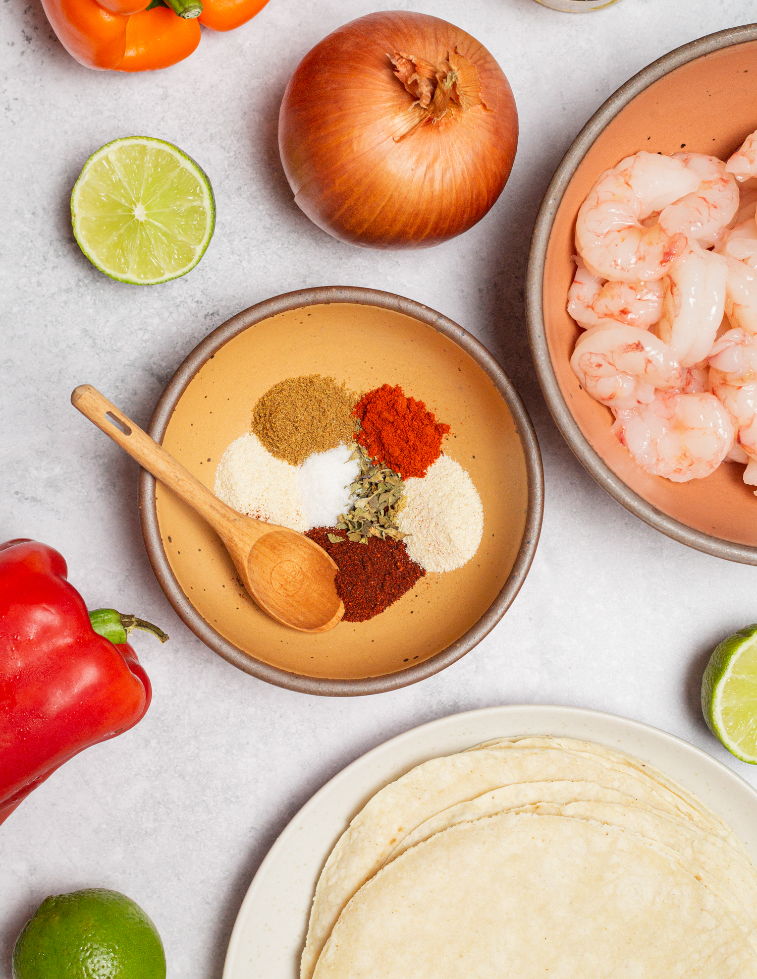Raw shrimp, spices, bell pepper, onion, lime and tortillas divided into portions.