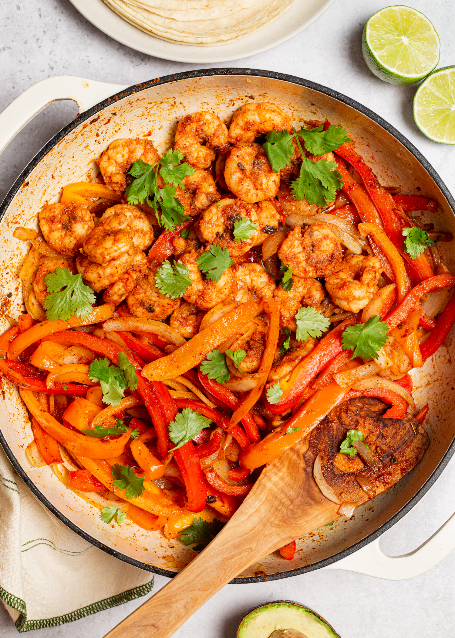 Seasoned shrimp and peppers cooked in a large pan.